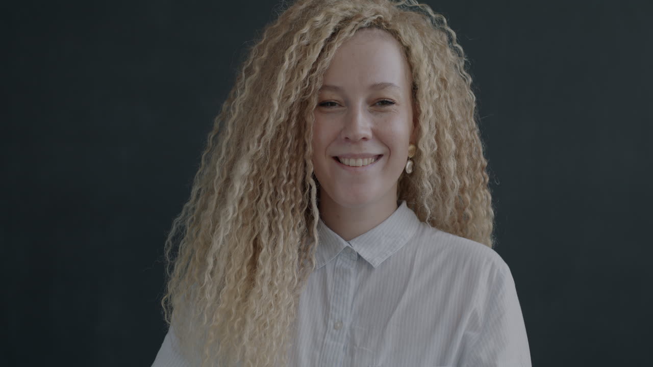 Smiling Woman with Curly Hair Making an OK Sign