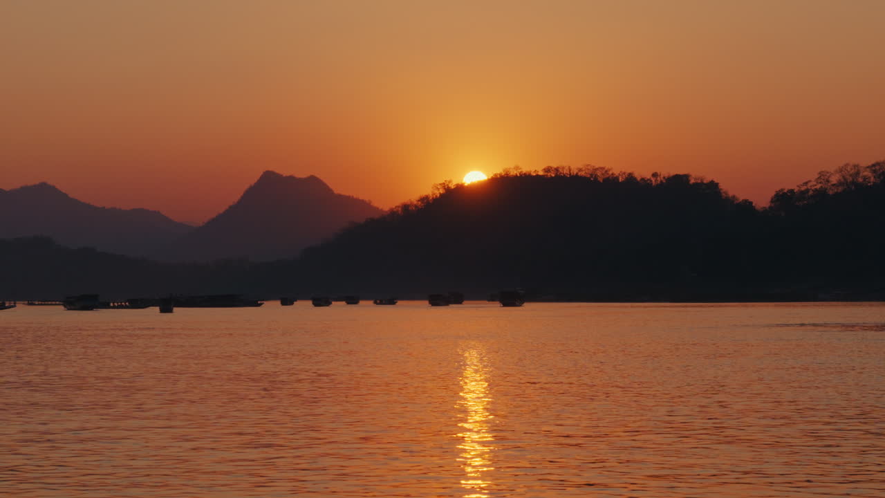 Sunset over a River with Mountains and Boats