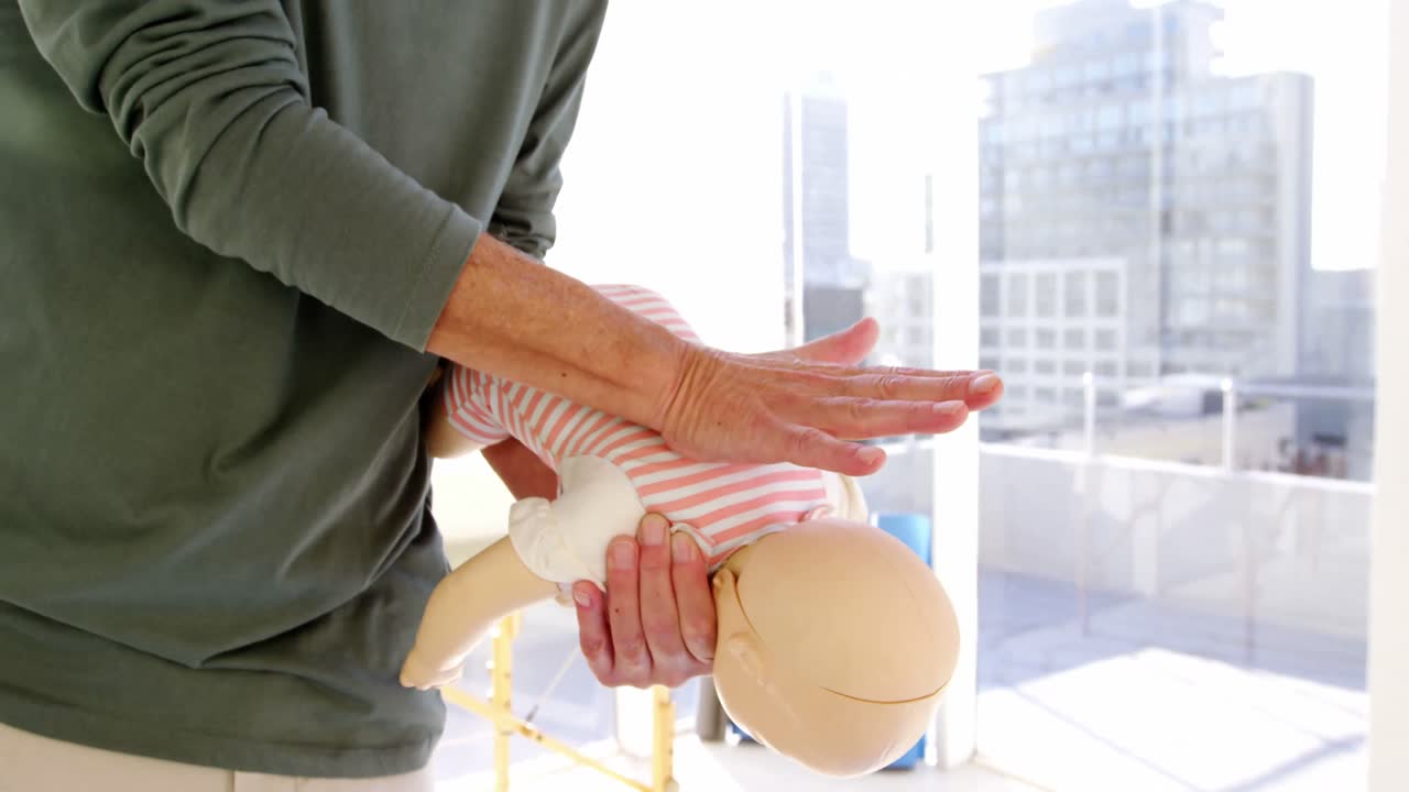 남자 구급대원 이 훈련 중 인형 의 등 을 문지르고 있다