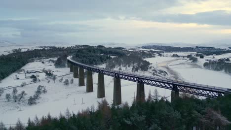 aerial ascending footage of snowed valley and famous historic findhorn viaduct over it