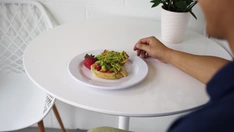 avocado toast and strawberry breakfast on a white table, camera panning from left to right