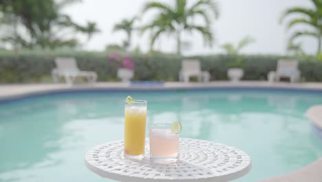 cóctel de jugo natural saludable con piscina y palmera en el fondo