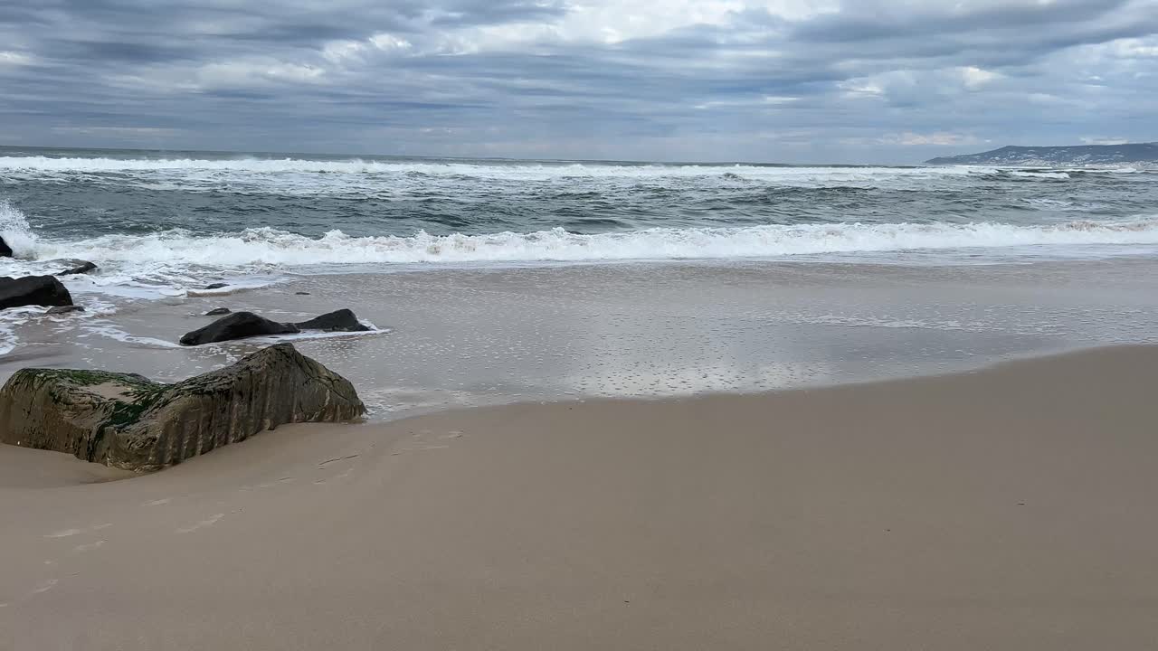 Atlantic waves rolling in on a sandy beach on a grey winter sky