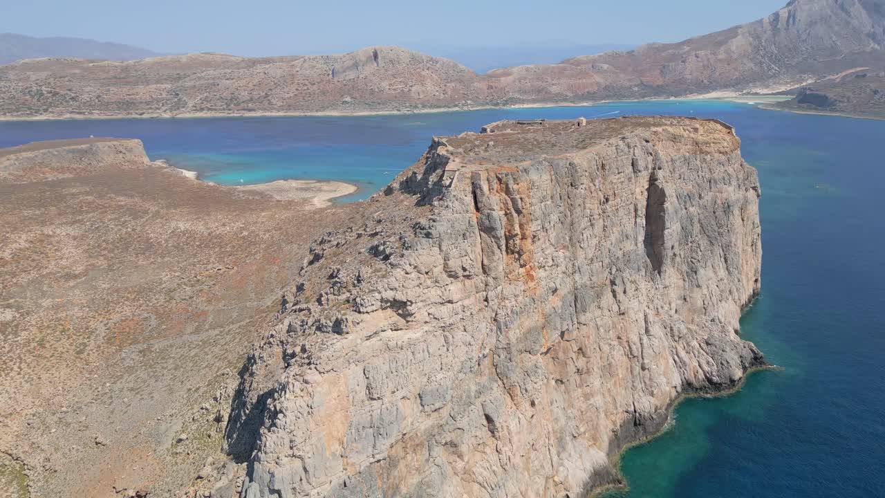 Orbit and panoramic view of Gramvousa with its steep cliffs, featuring Balos Beach’s turquoise waters in the background