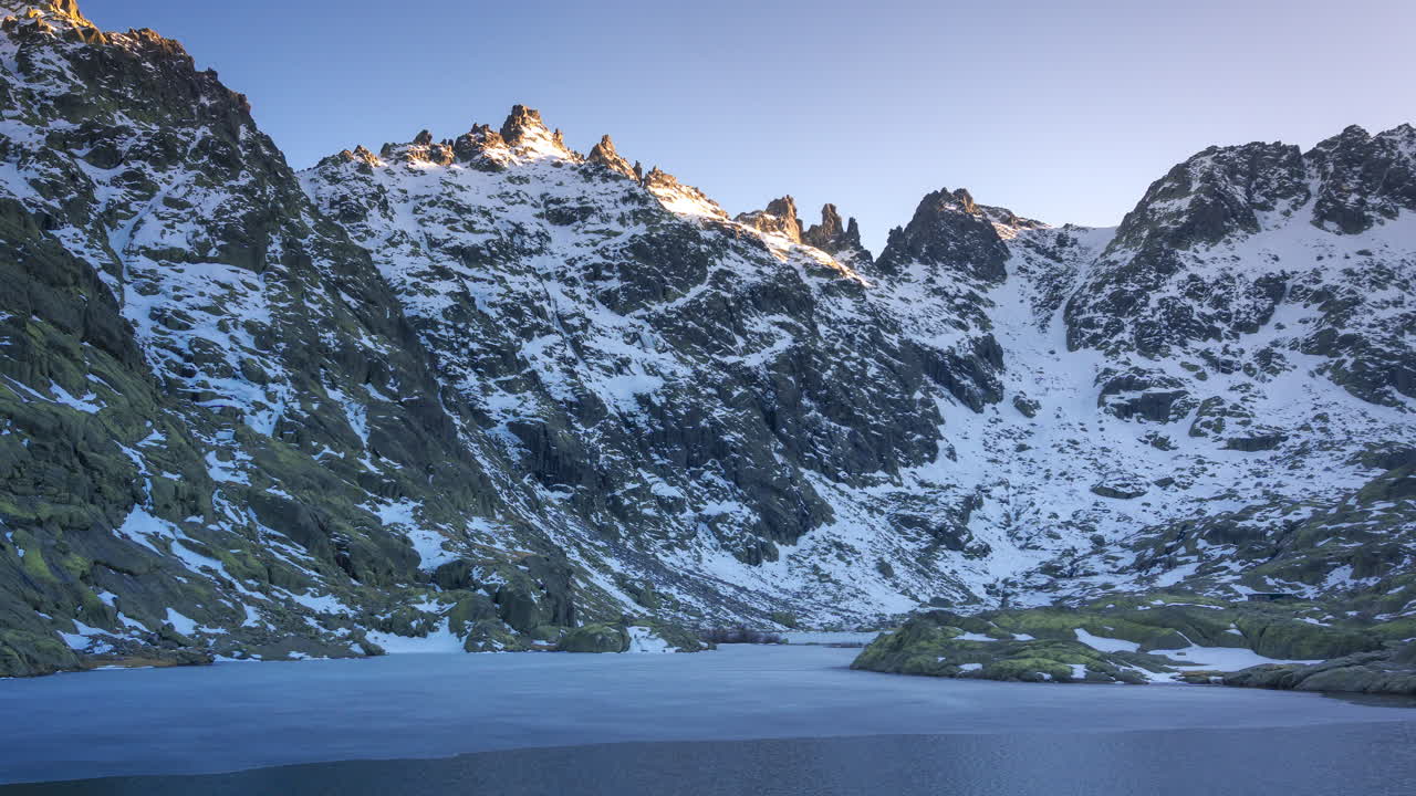 puesta de sol en la laguna grande de gredos, reflejo perfecto de las montañas en el lago medio congelado