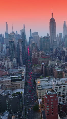 splendid panorama of beautiful new york at sun down. broad street full of cars having red lights on moving by. pink sky background. vertical video