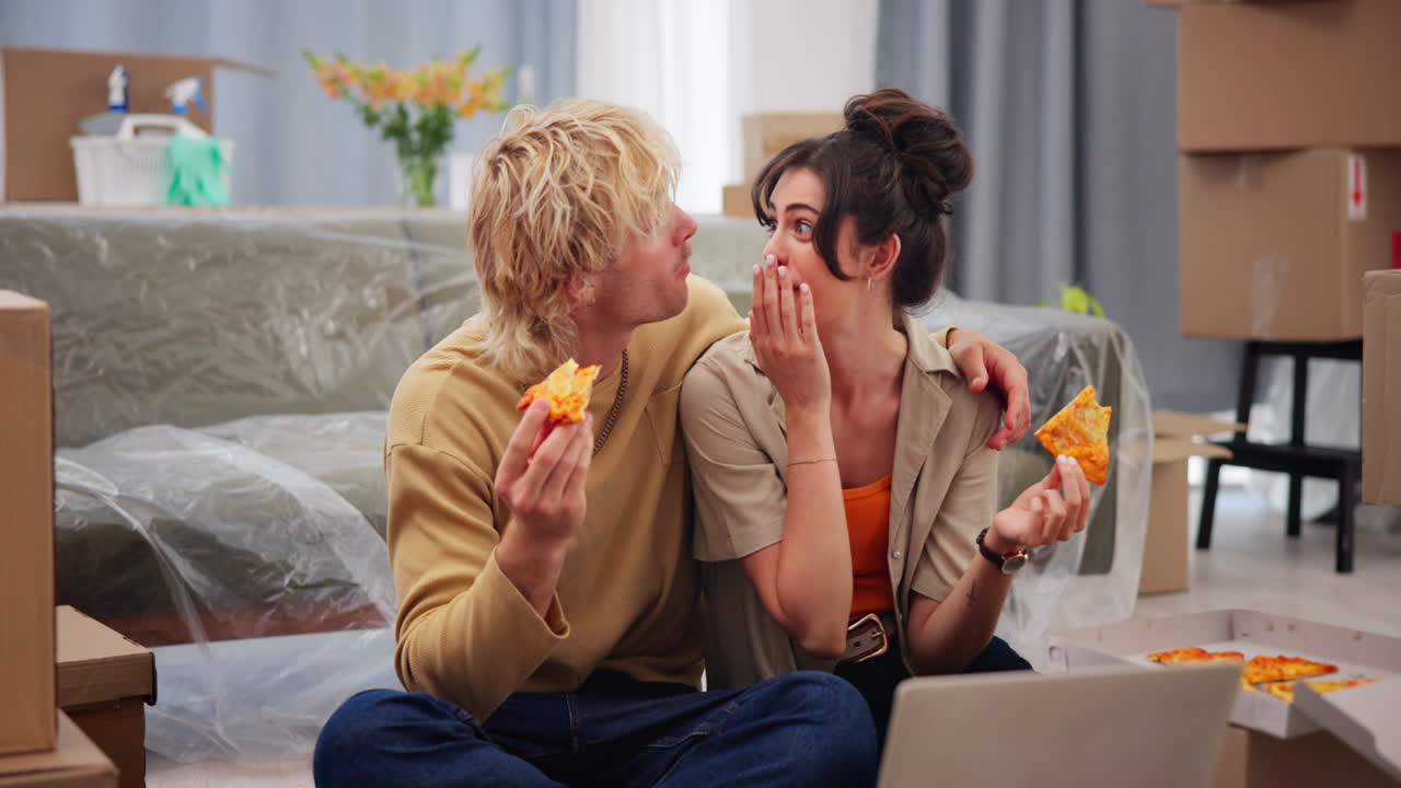 Young Couple Eating Pizza and Using Laptop in New Home