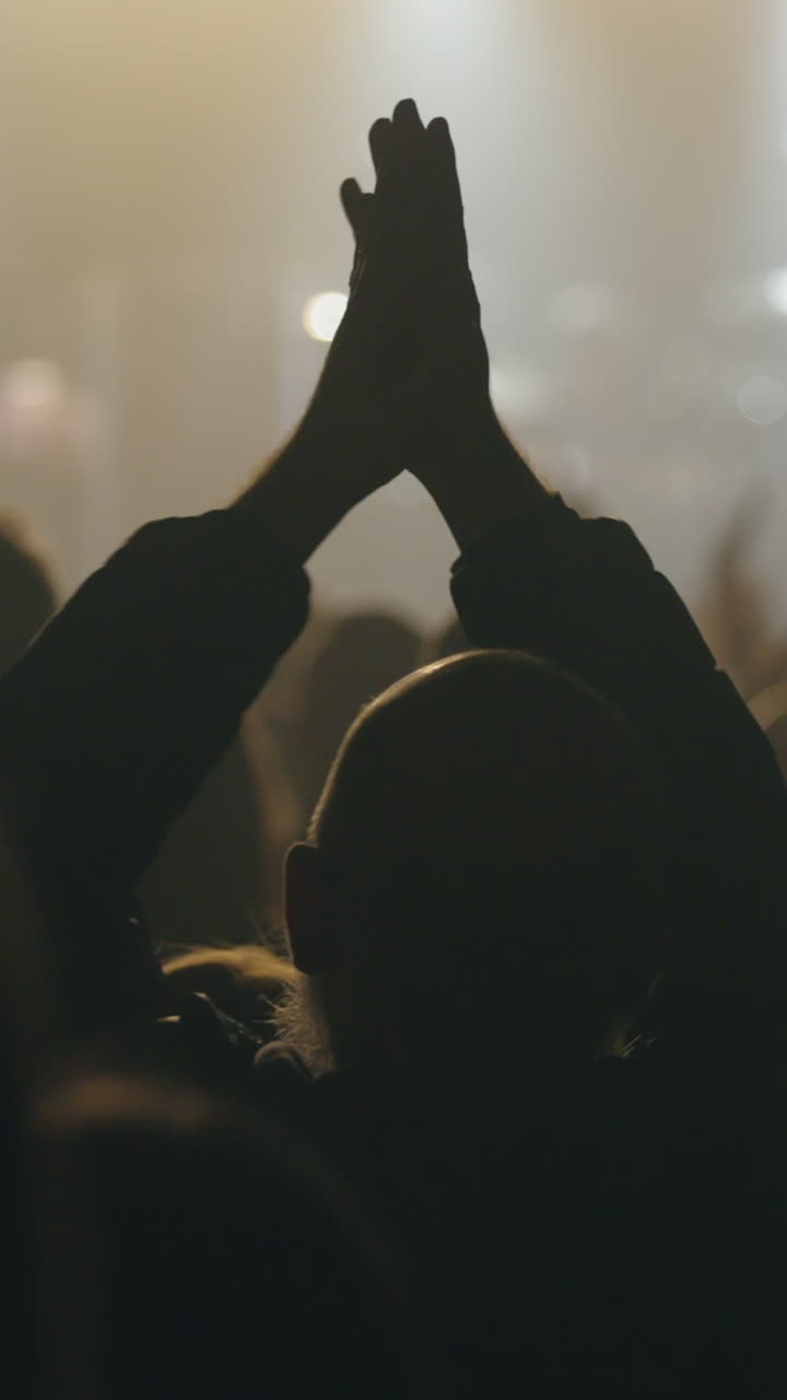 Audience Member Clapping Hands in Silhouette at Live Concert