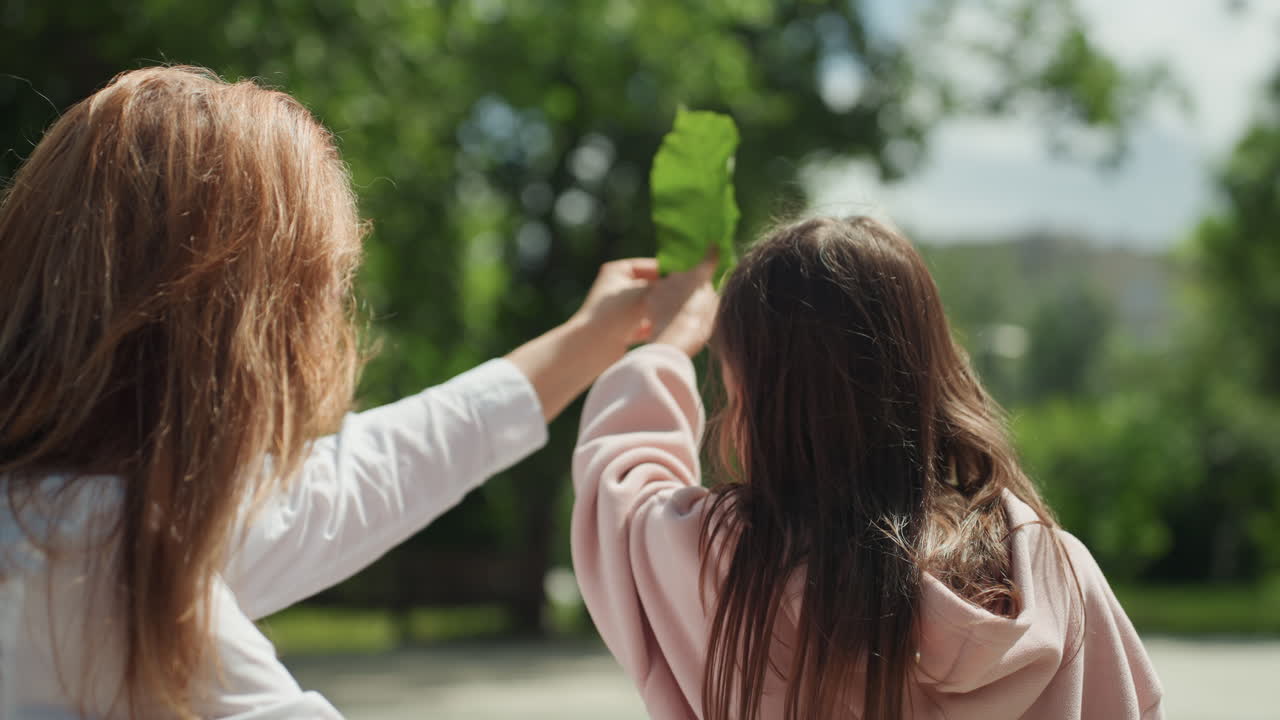Aprendizaje alegre al aire libre. Los lazos familiares crecen entre descubrimientos lúdicos en un entorno de parque soleado. Madre e hija se involucran con entusiasmo en la exploración de la naturaleza bajo la brillante luz del sol en el parque.