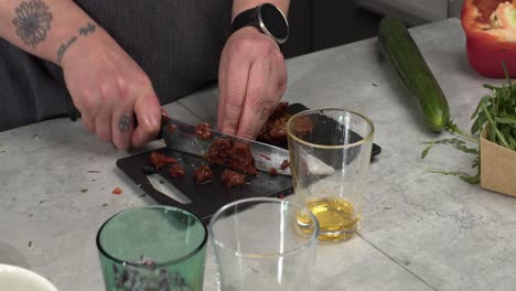 oily sundried tomato is cut up on small kitchen counter cutting board