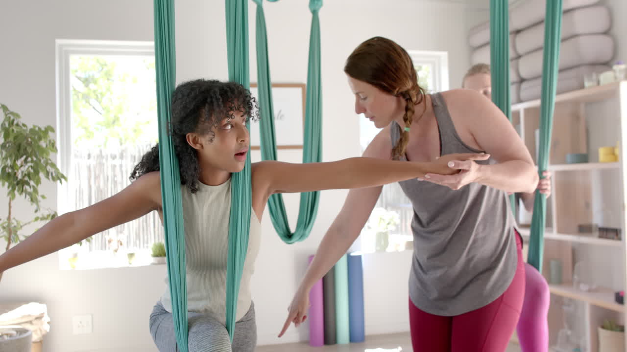 diversidad enfocada en el fitness adolescente haciendo ejercicio en clase de yoga aéreo y entrenadora femenina, cámara lenta