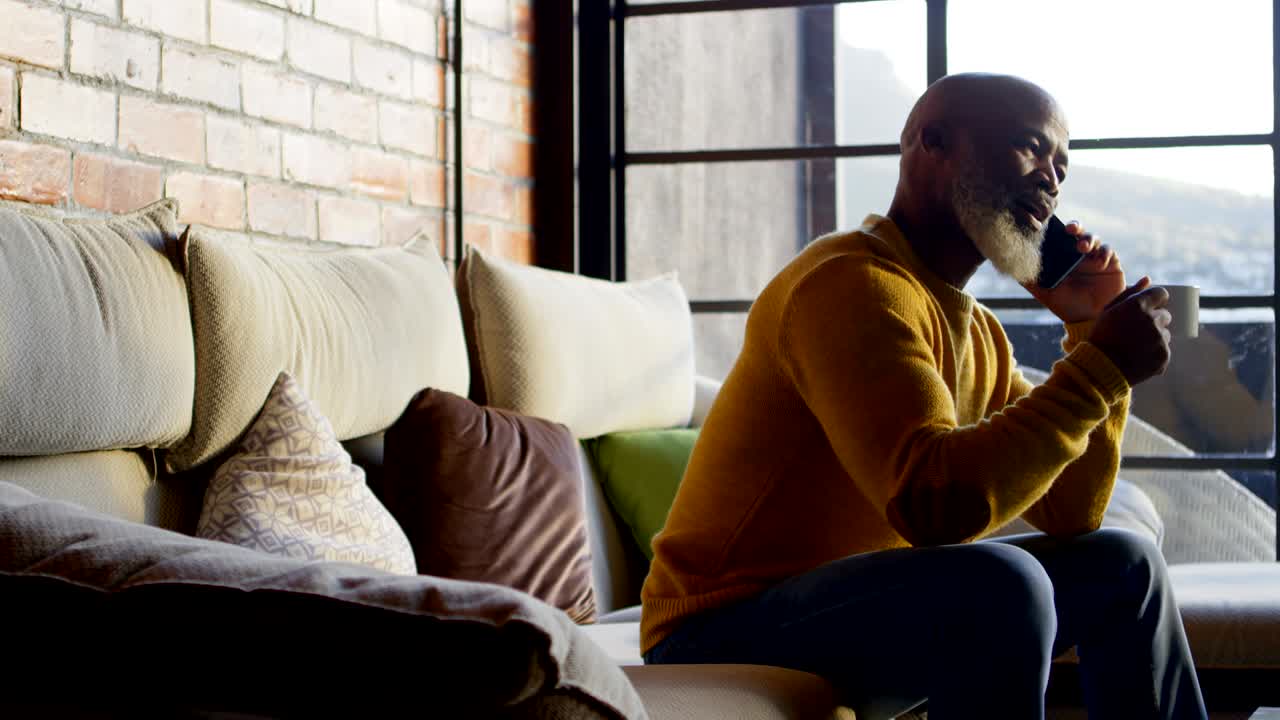 Senior man talking on mobile phone in living room 4k