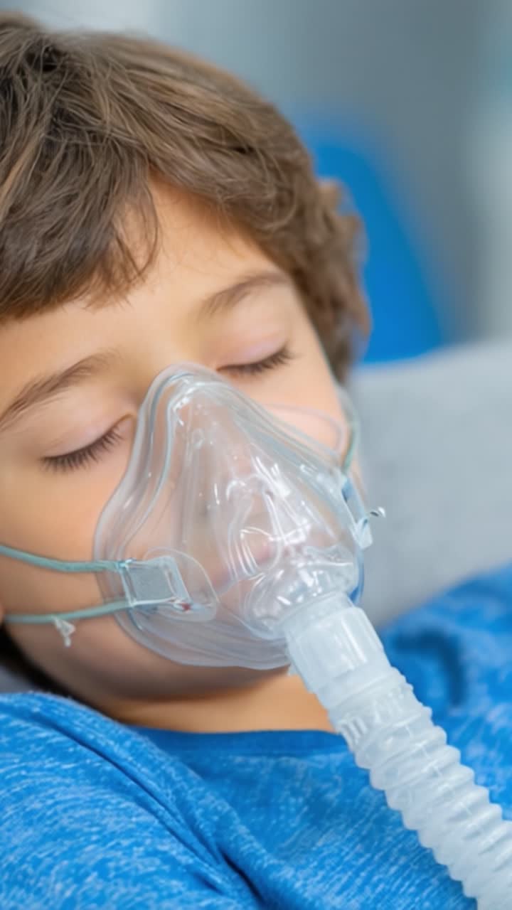 Un jeune enfant avec un masque respiratoire : Capturant le moment tendre d'un garçon se reposant confortablement tout en recevant une oxygénothérapie essentielle pour des difficultés respiratoires.