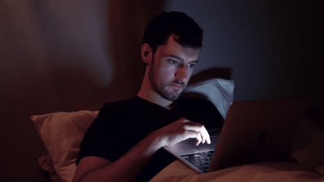 man with laptop in bed laughing joy emotion, evening night online internet, late work web browsing video watching on notebook before sleep