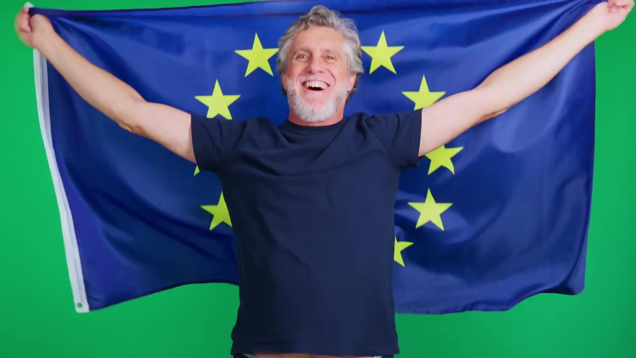 Uomo maturo felice che tiene e si avvolge nella bandiera dell'Unione Europea