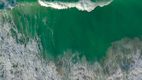vista aérea de las olas espumosas rodando en la playa en cámara lenta