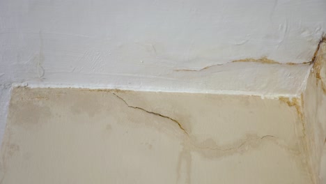 close up water damage and cracks slow panning right white and yellow beige wall corner, home repairs, home insurance, construction, business insurance, 4k