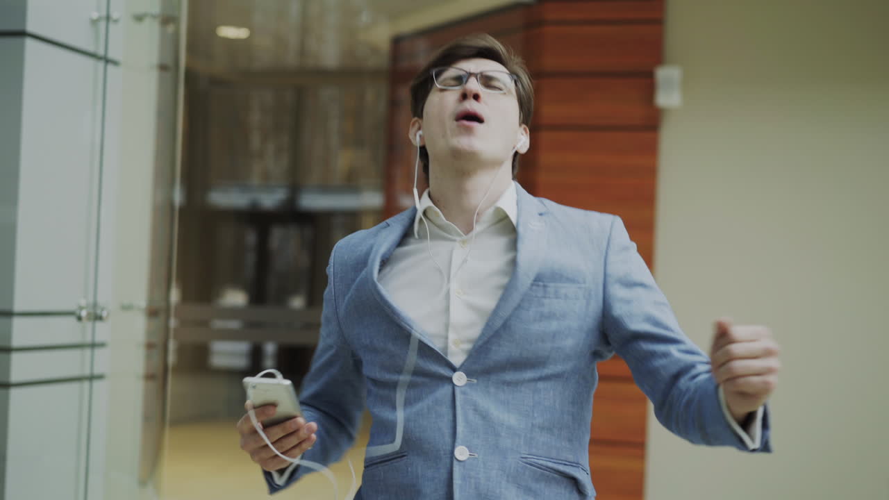 Businessman walking in office building listening to music