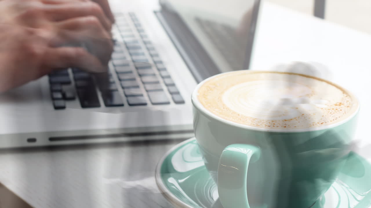 animación de las manos de una mujer caucásica usando una computadora portátil sobre una taza de café