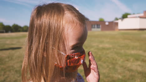 cute little girl turns around and takes her face mask off