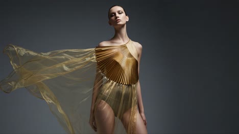 a captivating golden fashion showcasing elegant drapery and bold designs, highlighting a model with an airy sheer gold ensemble in a striking fashion setting