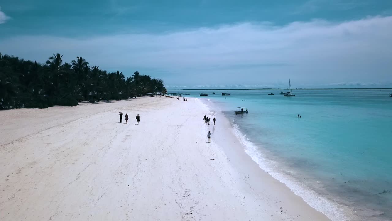 Philipp Marnitz tarafından 2019'da çekilmiş, Zanzibar, Afrika Tanzanya'daki cennet rüyası plajının beyaz kumları, turkuaz suları ve insanları üzerinde geriye doğru uçan bir dronun harika havadan görüntüsü. Sinematik vahşi doğa 1080, 60p.