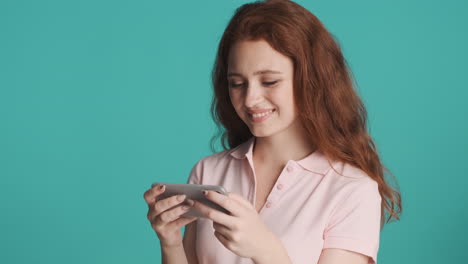 redheaded girl in front of camera on turquoise background.