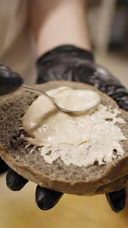 chef using spoon to spread mayonnaise on the wholemeal bread for the burger