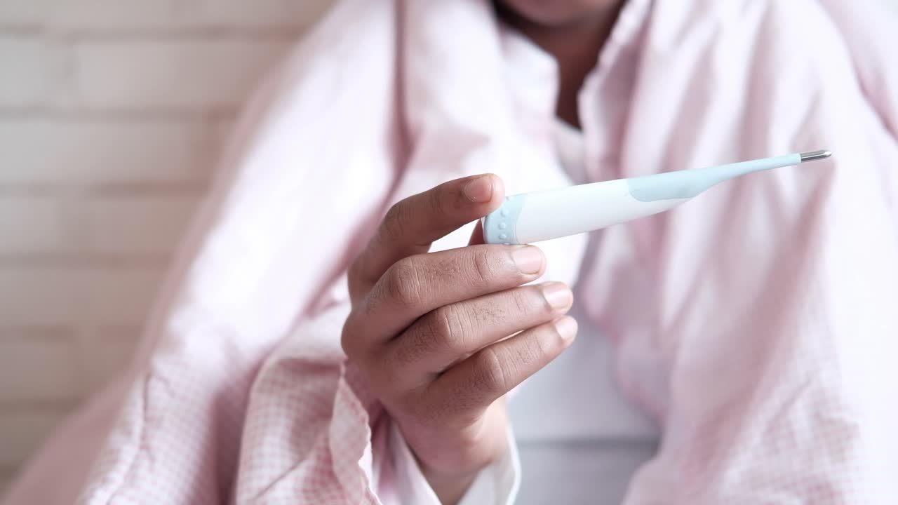 persona comprobando su temperatura con un termómetro