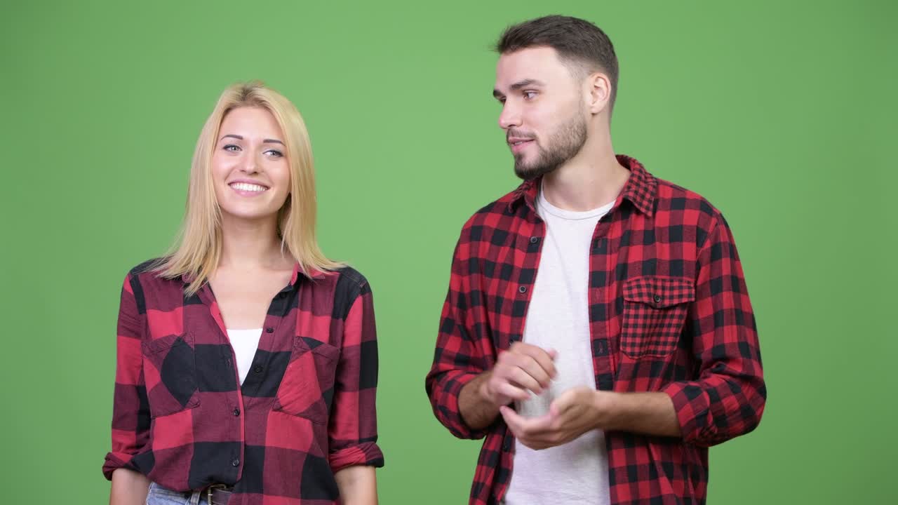 Young couple talking to camera together with young woman forgetting what to say