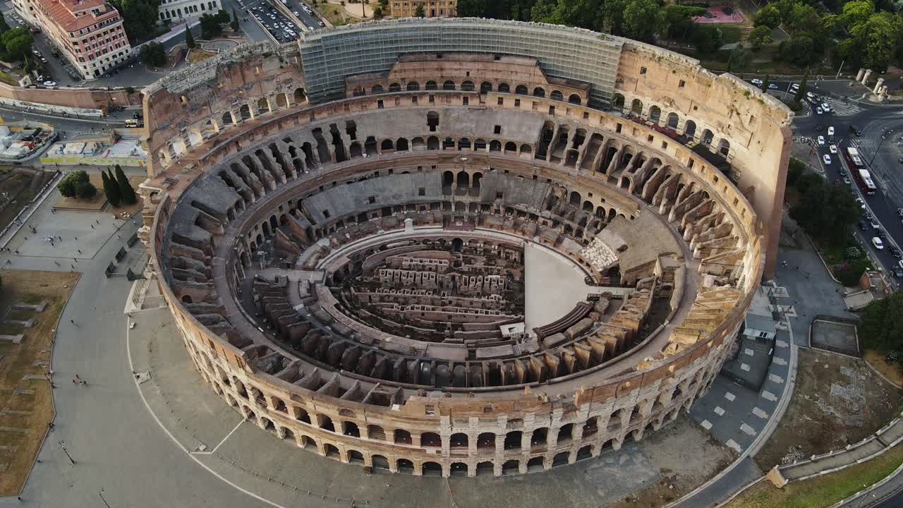 The Colosseum in Rome, seen from above, bathed in warm sunset hues with clouds