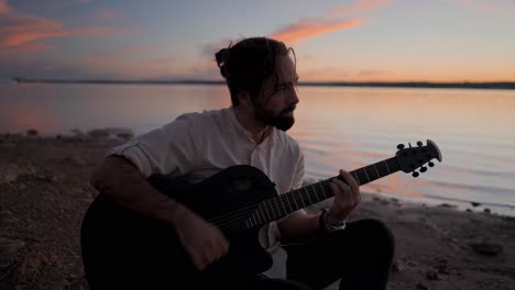 man playing guitar at sunset on the beach