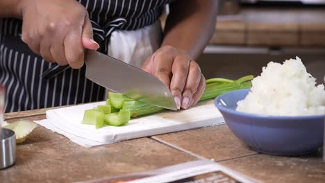 cortar apio orgánico para agregar a una receta casera - serie de gumbo en cámara lenta de vista lateral