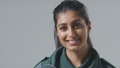 close up studio portrait of smiling young female paramedic against plain background