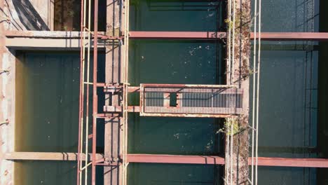 Paso-Elevado-A-Vista-De-Pájaro-De-Una-Estación-De-Agua-Abandonada-Ahora-Cubierta-De-Maleza-Y-Llena-De-Agua-De-Lluvia