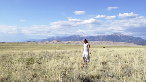 Die-Großen-Sanddünen,-Colorado-Nationalpark,-Spätsommer,-Schöne-Frau,-Model,-Schauspielerin,-Sonne,-Geküsst,-Friedlich,-Glücklich,-Entspannt,-Zehenspitzen,-Hohes-Goldenes-Gras,-Süßes-Kleid,-14er-Berggipfel,-Filmisch