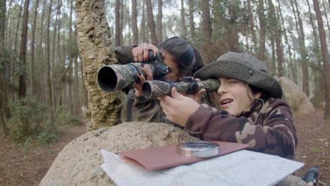 happy woman and her son birdwatching in a natural park