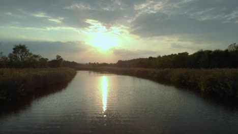 Disparo-De-Un-Dron-Bajo-Cerca-Del-Río-Que-Vuela-Río-Arriba-Al-Atardecer