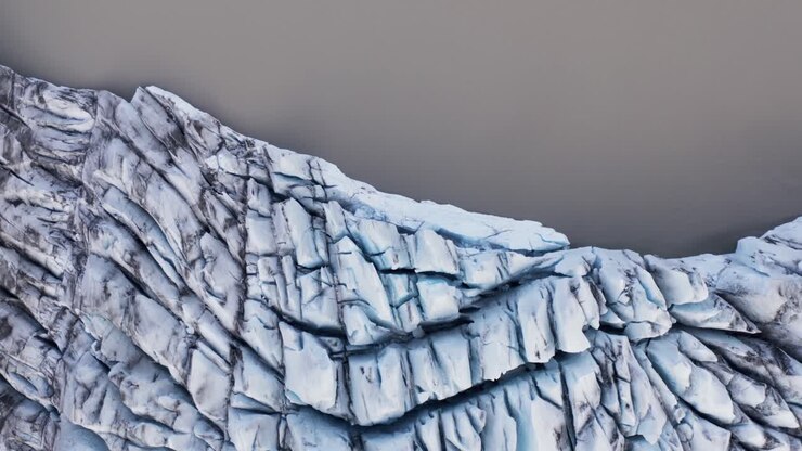 Above white glacier edge at brown lagoon water, top down