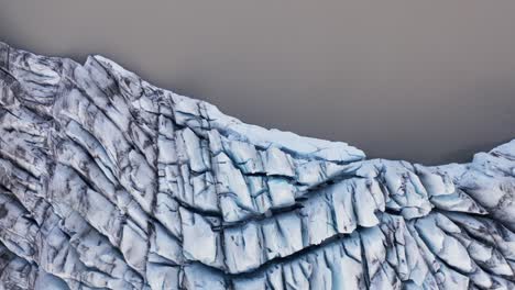 above white glacier edge at brown lagoon water, top down