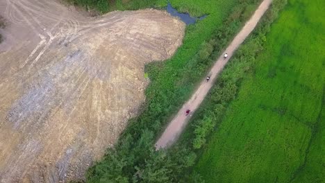 backpackers riding scooters through the rural farmland and countryside near siem reap, cambodia. aerial top down view