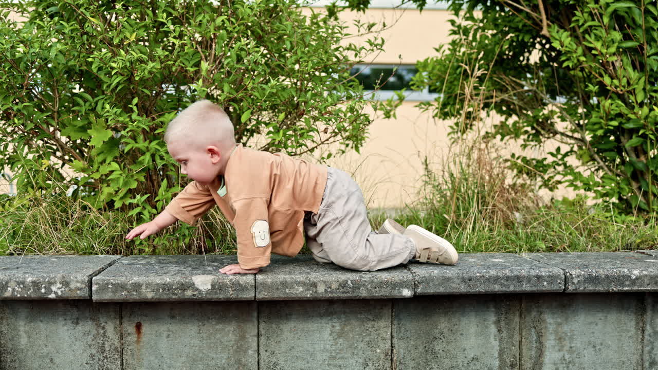 Un bambino piccolo in maglietta e jeans corre su un parco giochi all'aperto. Il bambino esplora l'ambiente. Un bambino cammina all'aperto nel parco giochi.