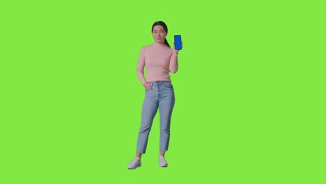 Studioporträt-In-Voller-Länge-Einer-Frau,-Die-Ihr-Bluescreen-Handy-In-Richtung-Kamera-Vor-Greenscreen-Hält-2