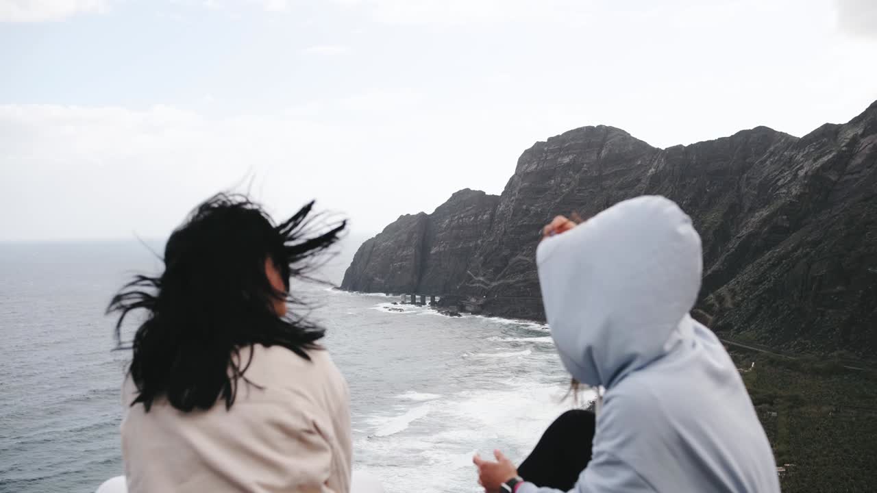 Two tourist woman looking at ocean view,  enjoying and calm landscape volcanic mountains background