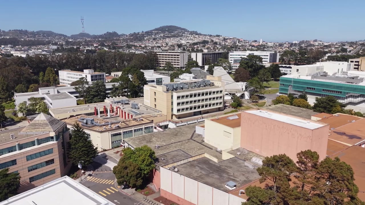 Maravillosa vista aérea del campus de la Universidad Estatal de San Francisco en un día soleado y brillante, con las colinas residenciales de la ciudad y la Torre Sutro visibles al fondo