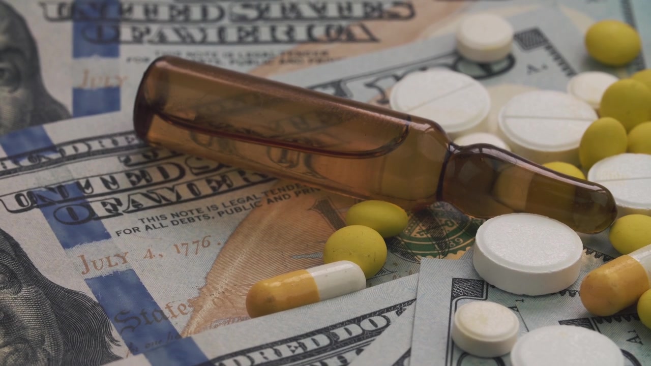Pillole mediche e fiala su banconote da dollari USA