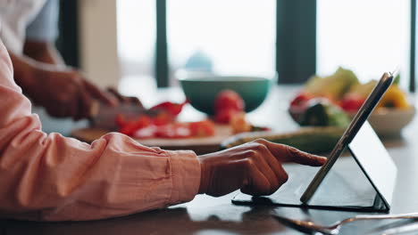 person using a tablet while preparing food in the kitchen