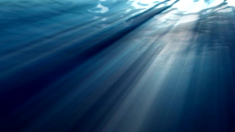 high quality looping animation of ocean waves from realistic underwater. light rays shining through