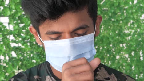 young man coughing while wearing a mask