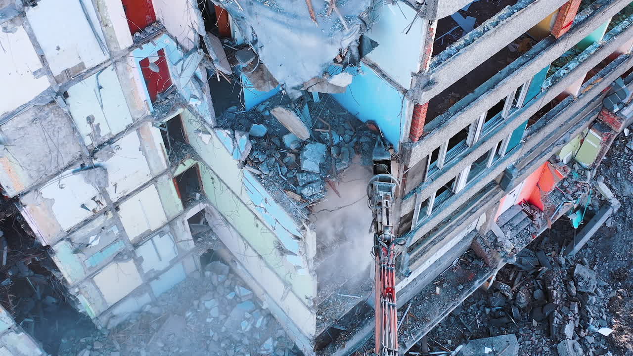 The removal of house wrecks after an earthquake. Dismantling of collapsed structures.Up view of excavator work with wrecks of ruined buildings.